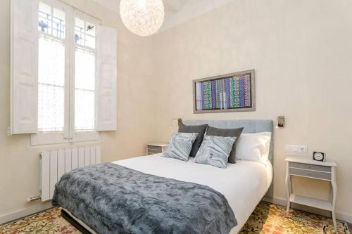 a bedroom with a large white bed and two windows at Lovely Designed House Connected To Center in Cornellà de Llobregat