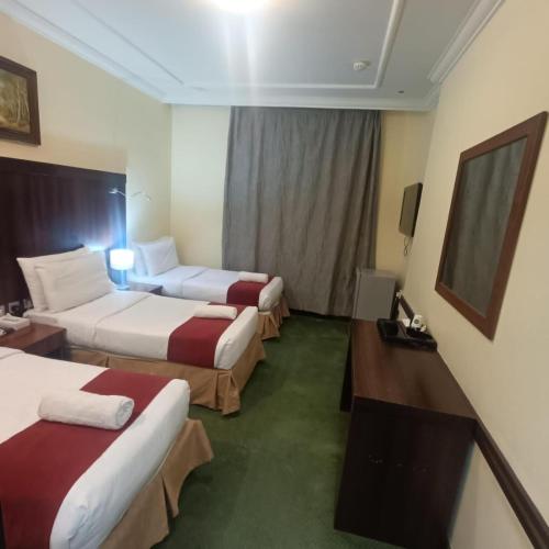 a hotel room with two beds and a television at Jadda Al Khalil Hotel in Al Masfalah