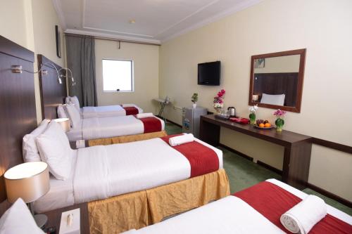 a hotel room with four beds and a mirror at Jadda Al Khalil Hotel in Al Masfalah
