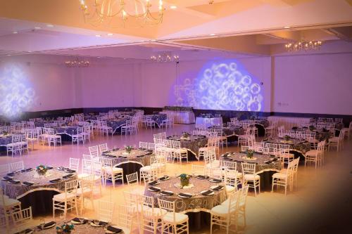プエブラにあるCourtyard by Marriott Puebla Las Animasのテーブルと白い椅子が備わる部屋