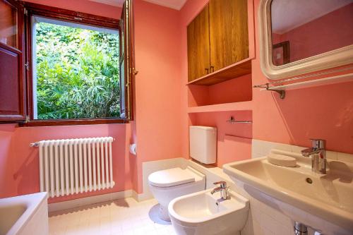 Un baño con inodoro, lavabo y ventana. en Villa Scagliola, en Verbania
