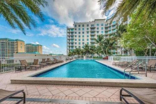 a swimming pool with chairs and a building at Amazing one-bedroom in Casa Costa!BEACH PASS INC! in Boynton Beach