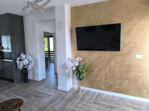 a living room with flowers and a television on a wall at Villa S in Vir