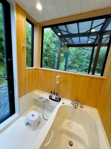 a bathroom with a tub with a toilet in it at Kaede 楓 in Kusatsu