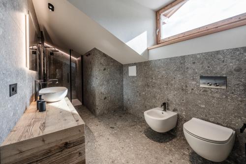 a bathroom with a sink and a toilet and a window at ALPEDOR Mountain Suites in Commezzadura
