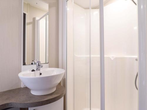a white bathroom with a sink and a shower at Sea Breeze C38 Dyffryn Seaside Estate in Dyffryn