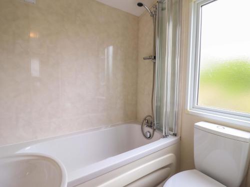a bathroom with a tub and a toilet and a sink at Beach Retreat E19 Dyffryn Seaside Estate in Dyffryn