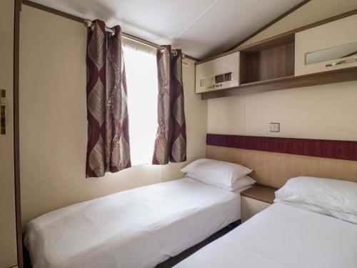 two beds in a small room with a window at Beach Retreat E19 Dyffryn Seaside Estate in Dyffryn