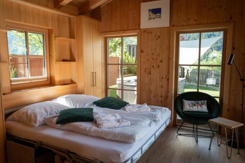 a bedroom with a large bed with a chair and windows at Chalet Hittli 1065 Tirol sauna garden WiFi guest card in Fliess