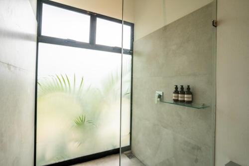 a shower with a glass door with bottles on a shelf at Anusara Dream Villa with Pool & AC in Talamanca