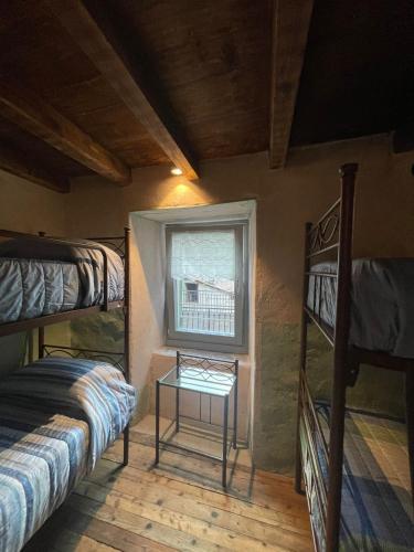 a room with bunk beds and a table and a window at ALBERGO DIFFUSO ORNICA NEL CUORE in Ornica