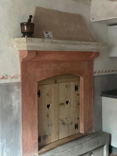 a fireplace with a wooden door on top of it at ALBERGO DIFFUSO ORNICA NEL CUORE in Ornica
