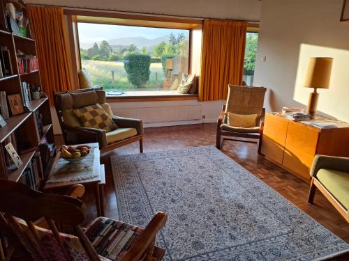 a living room with a large window and a couch and chairs at Aquila Retreats in Comrie