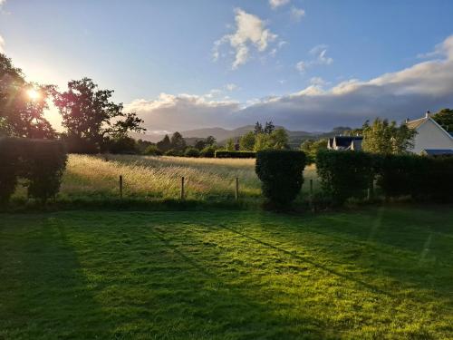 a field of grass with the sun in the background at Aquila Retreats in Comrie