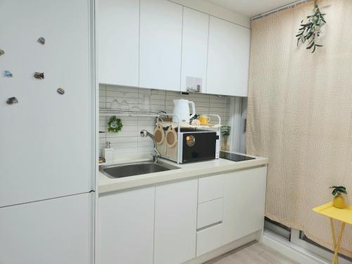 a white kitchen with a sink and a microwave at Gonghangdong Every moment in Seoul