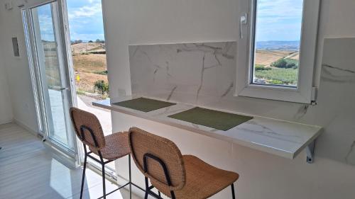 a kitchen with a counter with chairs and a window at Parthenope in Petacciato