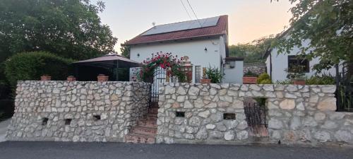 a stone fence in front of a white house at Tenkes-hegyi Vendégház in Siklós