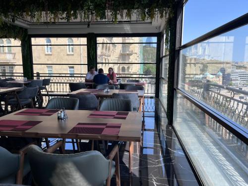 a restaurant with tables and chairs and a large window at ZamZam-Madinah Halal Hotels Group in Baku