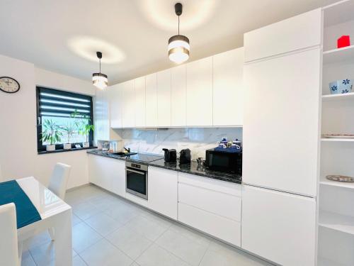 a white kitchen with white cabinets and a table at Transalpina Residence 17 in Alba Iulia
