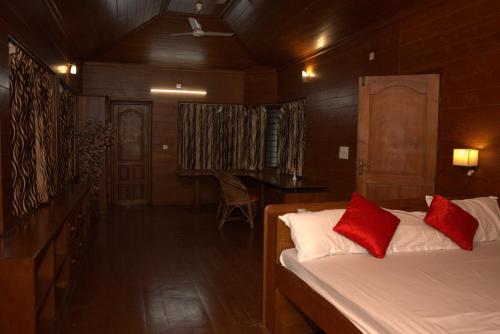 a bedroom with two beds with red pillows and a table at Mansion Du Lac kumarakom in Kumarakom