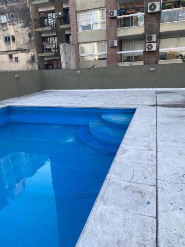a blue swimming pool in front of a building at Moderno departamento céntrico, con piscina-Barrio Norte in San Miguel de Tucumán