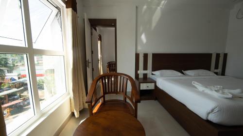 a bedroom with a bed and a large window at Lilly Ribera in Kumarakom