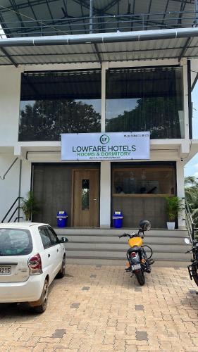 a motorcycle parked in front of a building with a car at Lowfare Hotels Medical College in Kozhikode