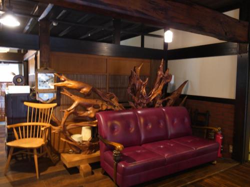 a living room with a red couch and a chair at Minshuku Takizawa in Takayama