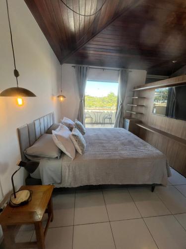 a bedroom with a bed and a table and a window at Apartamento Centro Búzios Luxo in Búzios