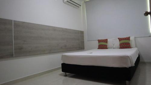 a white room with a bed with red and green pillows at D-rio Apto in Ríohacha