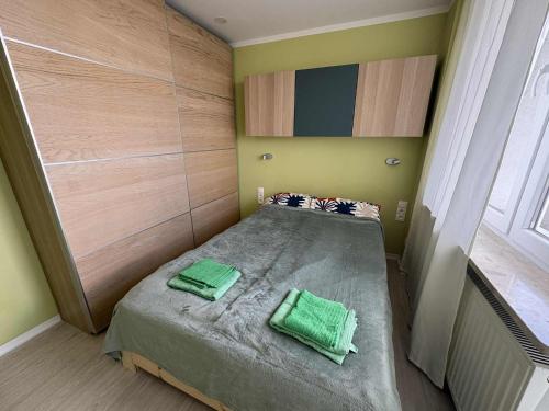 a small bedroom with a bed with two green pillows at Apartament Bazyliańska, metro Bródno in Warsaw