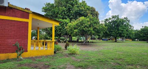 a yellow and red building with trees in a field at HOTEL CAMPESTRE CRISTALES cerca al mar By AMAUNA in San Bernardo del Viento