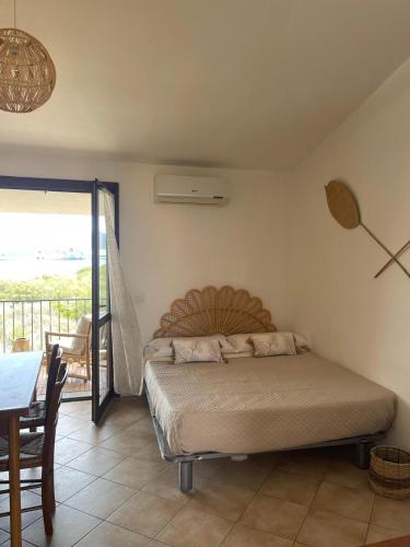 a bedroom with a bed and a table and a balcony at Studio Boho by Propertize in Olbia