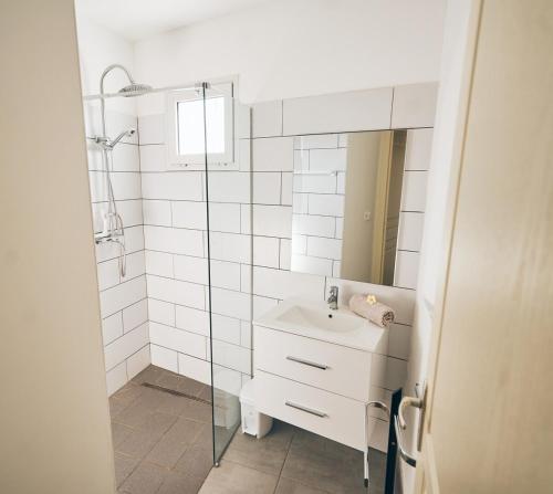 Un baño blanco con lavabo y ducha en KAP Alizés RDC appartement face à l'océan, en Saint-Pierre
