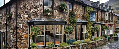 un edificio de piedra con ventanas y plantas. en Tanronnen Inn, en Beddgelert