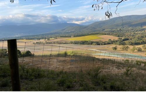 a fence with a view of a field and mountains at Vista Apartment 2 in Yarra Junction