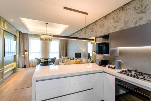 a kitchen with white cabinets and a living room at Steyn City Hotel by Saxon in Midrand