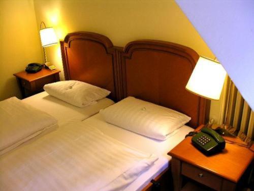 ein Schlafzimmer mit einem Bett mit Telefon und zwei Nachttischen in der Unterkunft Waldhotel Silbermühle in Horn-Bad Meinberg