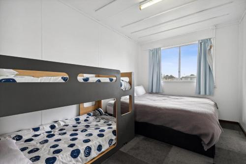 a bedroom with two bunk beds and a window at Vintage Ledge Point Beach Shack in Ledge Point