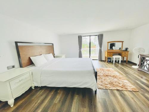 a bedroom with a large white bed and a wooden floor at lalahouse6 in Khu Chi Lăng