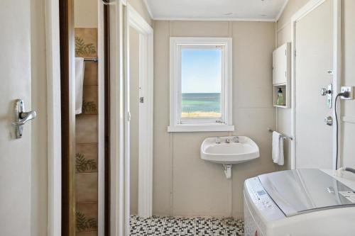 ein Badezimmer mit Waschbecken und Fenster in der Unterkunft The Blue Beach House, 3 star accommodation 5 star view in Ledge Point