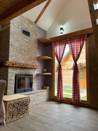 a living room with a fireplace and a large window at Vikendice Jovicic in Bukorovac