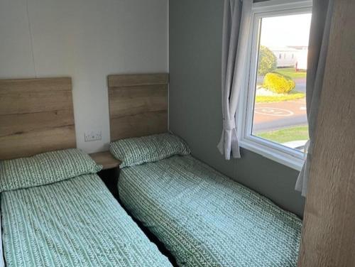 two beds in a small room with a window at Seaside Caravan in Eyemouth in Eyemouth