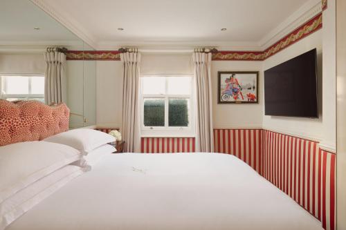 a bedroom with a white bed and a flat screen tv at Milestone Hotel Kensington in London