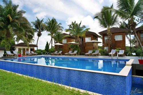 a swimming pool in front of a house with palm trees at River Lodge Resort in Ntchogo