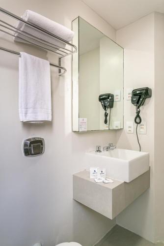 a white bathroom with a sink and a mirror at Valerim Florianópolis in Florianópolis