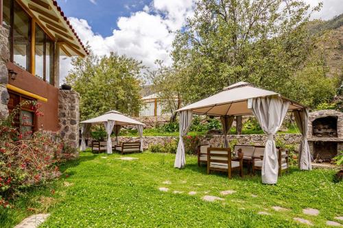 a garden with tables and chairs under umbrellas at Hermosa casa confortable en el Valle Sagrado in Calca