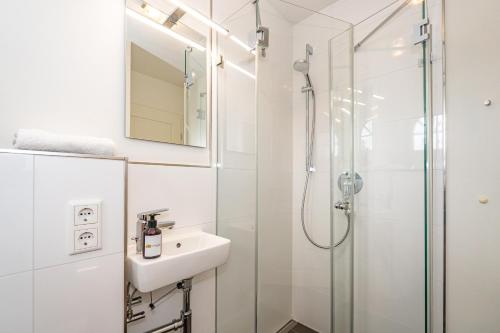 a white bathroom with a sink and a shower at Gode Stuv in Westerland