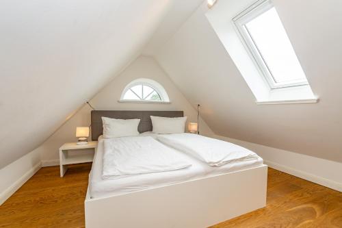 a bedroom with a white bed and two windows at Gode Stuv in Westerland