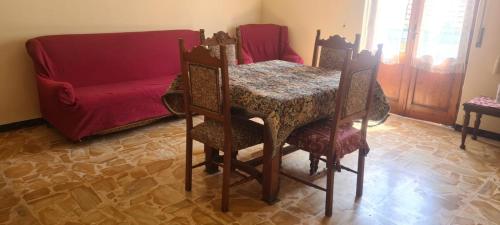 a dining room table and chairs with a red couch at Casa Di Alfredo in Lazzaro